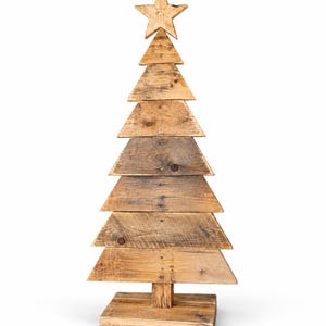 Könnte beinhalten: Eine dekorative Weihnachtsbaumskulptur aus gestapelten, horizontalen Brettern aus hellem Altholz. Die Struktur hat eine dreieckige Silhouette mit einem fünfzackigen Stern als Spitze und steht auf einem rechteckigen Holzsockel.