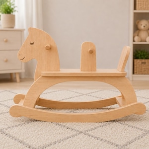 May include: A light-coloured wooden rocking horse featuring a smooth finish, a simple head design with closed eyes and a small smile, a central seat support, and a small tail piece. The structure is built with curved rockers for movement.