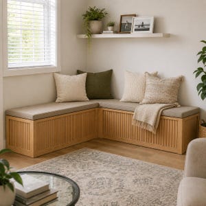 May include: An L-shaped wooden storage bench with vertical slat detailing and a light beige seat cushion. The bench is adorned with four square throw pillows in cream and olive green, plus a draped cream-colored knit throw blanket.