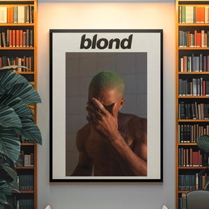 May include: Framed art print featuring the word "blond" in bold white letters. The image within the frame depicts a person with green hair covering their face. The artwork is displayed in a room with bookshelves and a bench.
