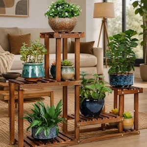 May include: A multi-tiered wooden plant stand with a dark brown finish, featuring several horizontal slatted shelves at varying heights. The stand holds multiple potted plants in various ceramic containers, including blue, green, and textured earth-toned pots.