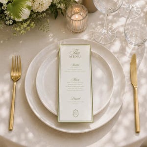 May include: A sophisticated table setting with gold cutlery, white plates, and a menu card. The menu card reads "The Menu" and lists courses. The table is decorated with flowers and candles, creating a refined atmosphere.