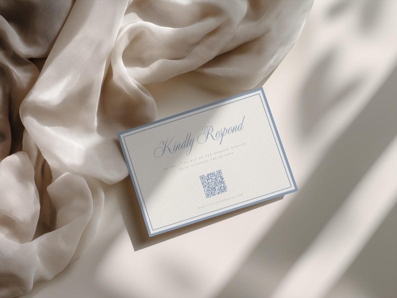 May include: A rectangular RSVP card with a light blue border on a cream background. The text reads Kindly Respond in a script font, with smaller text below and a QR code in the center. A website URL is printed at the bottom of the card.