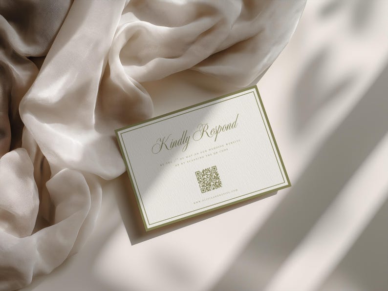 May include: A rectangular invitation card with the text "Kindly Respond" in elegant script. The card has a white background with a green border and a QR code. A soft, beige fabric is draped in the background.