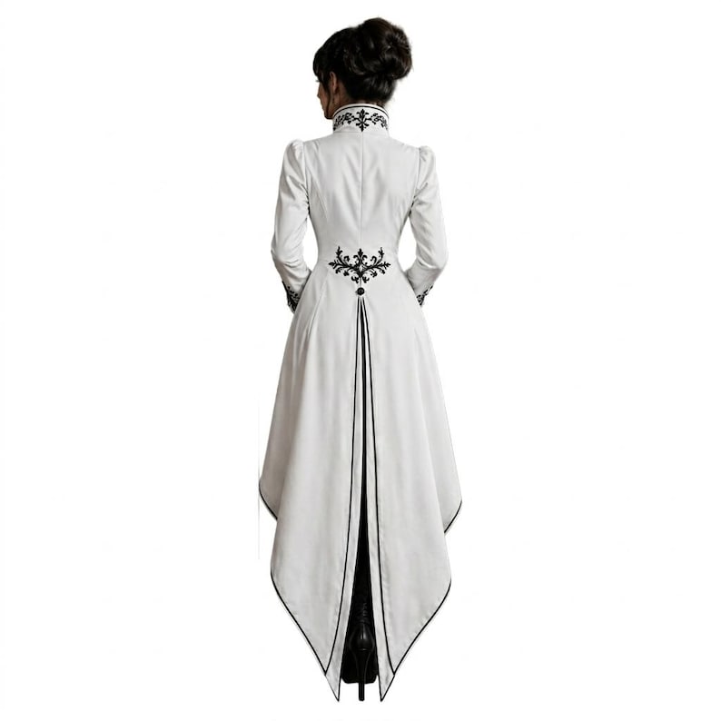 May include: A white, long-sleeved coat with black embroidered details. The coat features a high collar, decorative embroidery on the back, and a split, asymmetrical hemline. The coat is a unique piece of apparel.