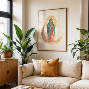 Puede incluir: Una l&aacute;mina de arte mural enmarcada con una ilustraci&oacute;n en acuarela de la Virgen de Guadalupe de pie sobre una luna creciente con un halo de rayos dorados detr&aacute;s de su cabeza, en tonos verde azulado, rojo y dorado sobre fondo claro.