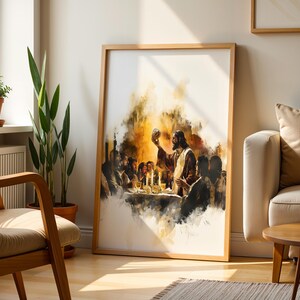 K&ouml;nnte beinhalten: Ein gerahmter vertikaler Wandkunstdruck mit einer Illustration des Abendmahls im Aquarellstil. Das Kunstwerk zeigt eine zentrale Figur, die einen Kelch an einem Tisch h&auml;lt, umgeben von anderen Personen, in warmen Gold- und Braunt&ouml;nen auf wei&szlig;em Grund.