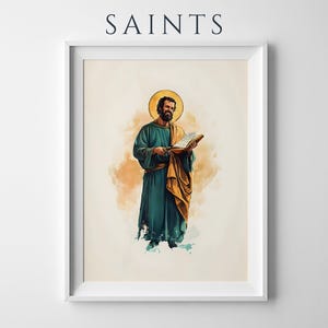 Op de afbeelding: Een ingelijste muurkunstprint met het woord SAINTS bovenaan. De illustratie toont een bebaarde figuur met een gouden halo, gekleed in een blauwgroene mantel en een okerkleurige sjaal, die een open boek vasthoudt. Aquarelstijl op een cr&egrave;mekleurige achtergrond.