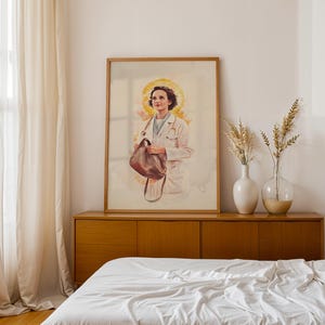 Puede incluir: Una l&aacute;mina de arte vertical enmarcada que presenta una ilustraci&oacute;n estilo acuarela de una persona con bata m&eacute;dica blanca y estetoscopio al cuello, sosteniendo un bolso de cuero marr&oacute;n, sobre un fondo circular amarillo suave tipo halo.