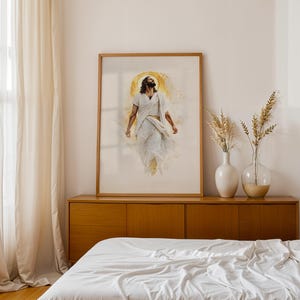 Puede incluir: Una impresi&oacute;n de arte mural enmarcada que presenta una ilustraci&oacute;n estilo acuarela de una figura con cabello oscuro largo y barba, vistiendo t&uacute;nicas blancas, con un efecto de halo dorado detr&aacute;s de la cabeza, sobre un fondo claro en un marco de madera.
