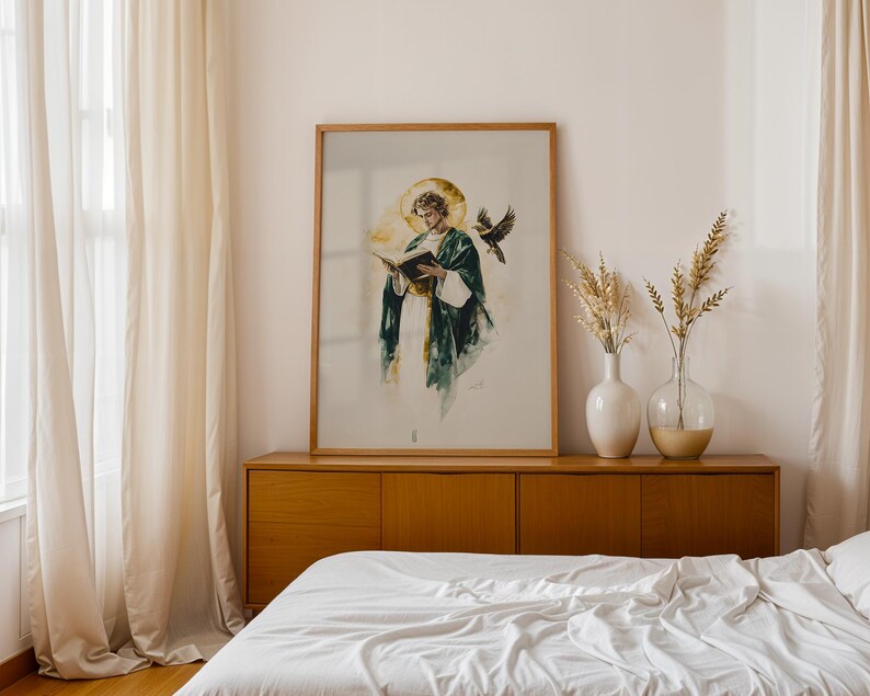 Pu&ograve; includere: Una stampa incorniciata in stile acquerello che raffigura una figura con una veste verde scuro e un'aureola dorata, intenta a leggere un libro aperto, accompagnata da un uccello in volo. L'opera &egrave; presentata in una cornice di legno chiaro.
