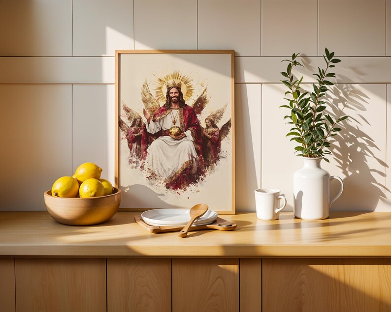 May include: A framed wall art print depicting a central figure with a crown and halo, flanked by two winged angels, holding a golden orb. The artwork features a white and red colour palette with a watercolour-style aesthetic and a light wood frame.