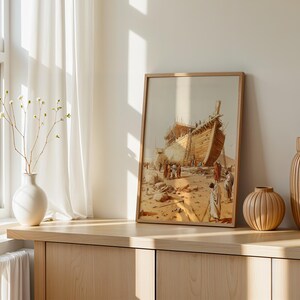 May include: A framed wall art print depicting a large wooden ship under construction in a desert landscape with figures in robes standing nearby. The artwork features warm beige and brown tones, showcasing the hull of the vessel and scaffolding.