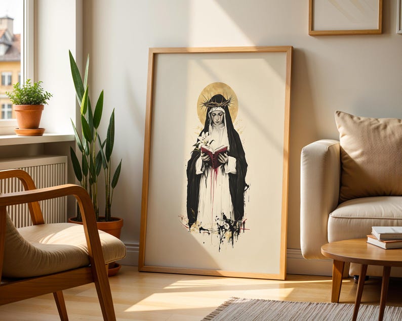 May include: A framed vertical art print featuring a stylized illustration of a figure in a black habit and white veil, wearing a crown of thorns. The figure holds an open book with red pages and a white lily, set against a gold halo background.