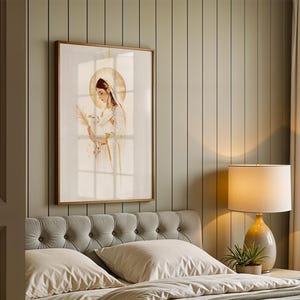 May include: A framed wall art print featuring a watercolour-style illustration of a figure with a golden halo, wearing a white head covering and robe, holding a white dove and a palm frond, rendered in soft neutral tones with gold accents.