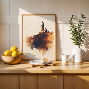 May include: A framed print featuring a silhouette of a figure standing on a cliff edge, displayed on a wooden counter with a bowl of yellow lemons, a stack of white plates, a wooden spoon, a white ceramic mug, and a white vase with green leaves.