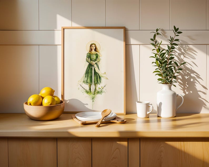 Op de afbeelding: Een ingelijste kunstdruk met een aquarelillustratie van een figuur in een groene jurk die een zwaard vasthoudt en rechtop staat. Het kunstwerk zit in een lichthouten lijst, naast een kom met gele citroenen en een witte vaas met groen.