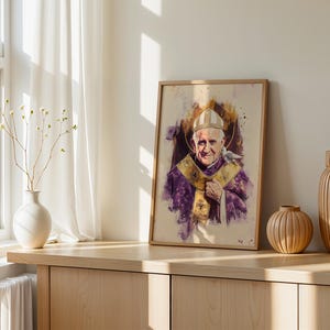 K&ouml;nnte beinhalten: Ein gerahmtes Portr&auml;t im Aquarellstil von Papst Johannes Paul II., der eine wei&szlig;e Mitra und violette Gew&auml;nder mit einer goldenen Stola tr&auml;gt. Eine kleine wei&szlig;e Taube ruht auf seiner Schulter. Das Kunstwerk zeigt violette und goldene Farbspritzer auf einem cremefarbenen Hintergrund.