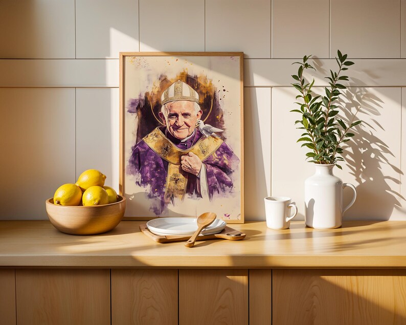 Peut inclure: Un portrait encadr&eacute; style aquarelle du Pape Jean-Paul II portant des v&ecirc;tements liturgiques violets et dor&eacute;s ainsi qu'une mitre blanche, avec une colombe blanche sur l'&eacute;paule. L'&oelig;uvre est pos&eacute;e sur un comptoir en bois pr&egrave;s d'un bol de citrons.