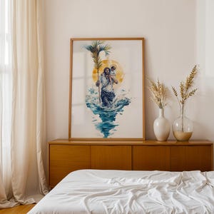 May include: A framed vertical art print featuring a watercolor illustration of a figure carrying a child on their shoulders while walking through blue water. The figure holds a tall palm frond, with a large yellow sun halo behind their heads.