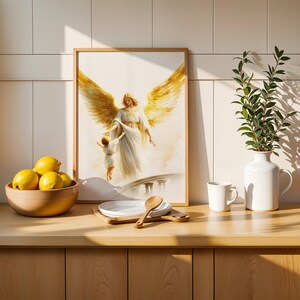 May include: A framed wall art print depicting an angel with large golden wings reaching down to hold the hand of a small child. The artwork is rendered in soft, light tones and is displayed in a simple wooden frame on a kitchen counter.