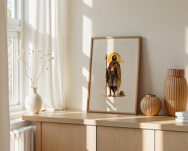 May include: A framed wall art print featuring a watercolour-style illustration of a figure with a beard, wearing a brown robe and holding a tall wooden staff. A golden circular halo is positioned behind the head of the figure, who stands barefoot.