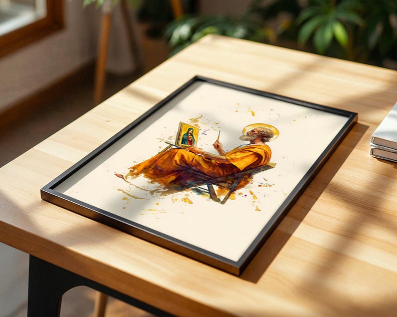 May include: A framed print featuring a watercolour-style illustration of a bearded figure in orange robes sitting on a chair, holding a brush and painting a small portrait of a woman in blue and red robes, accented with yellow paint splatters.