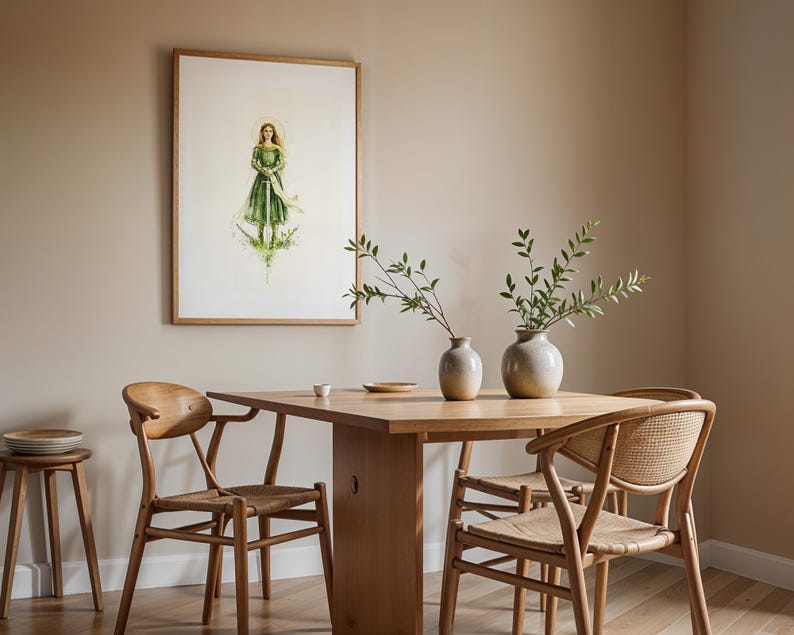 Op de afbeelding: Een ingelijste aquarelillustratie van een figuur in een groene jurk die een zwaard vasthoudt, boven een houten eettafel met twee keramische vazen met groene takken, vergezeld door drie houten stoelen met gevlochten zittingen en een krukje.