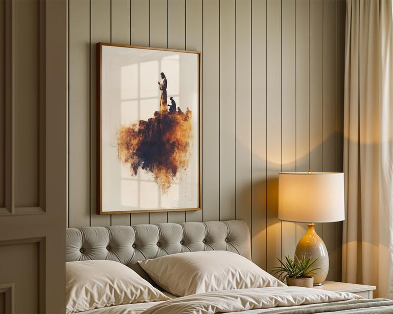 K&ouml;nnte beinhalten: Ein gerahmter Wandkunstdruck mit der Silhouette einer Figur, die auf einer felsigen Klippe steht, mit einem leuchtend orangefarbenen und dunkelbraunen Aquarell-Wolkeneffekt unter der Landmasse, vor einem schlichten wei&szlig;en Hintergrund.