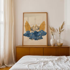 May include: A framed wall art print featuring two cherubs with large golden wings resting on a dark blue cloud filled with small yellow stars. The illustration is set against a light beige background and enclosed in a simple wooden frame.