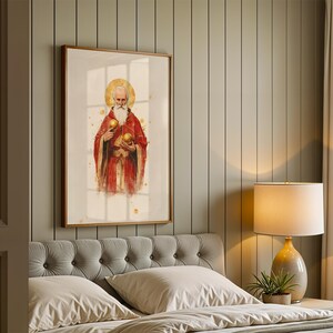 May include: A framed wall art print featuring a bearded figure in a red robe with a gold halo, holding two golden spheres. The artwork is rendered in a watercolour style with gold splatter accents, presented in a simple wooden frame.