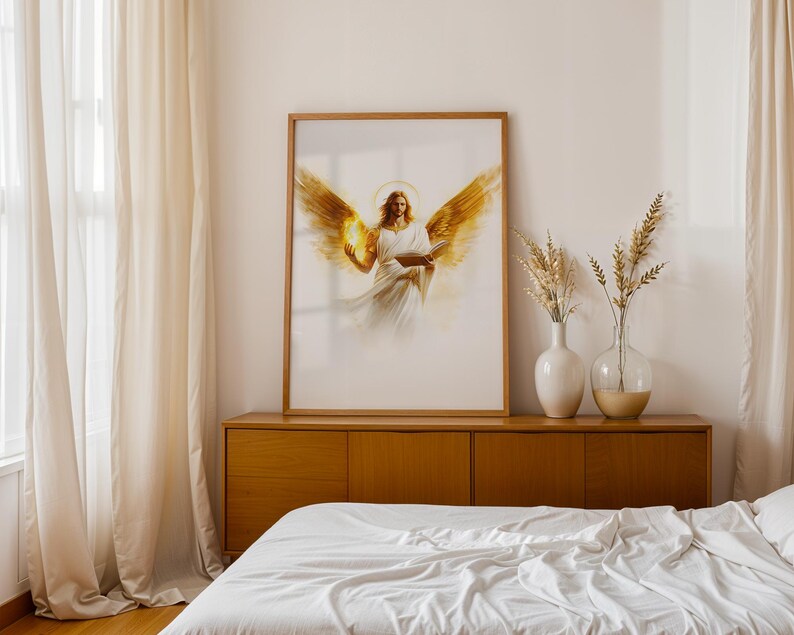 May include: A framed vertical wall art print featuring a central figure with large golden wings, a glowing halo, and flowing white robes, holding an open book. The artwork is displayed in a light wood frame on a wooden sideboard surface.