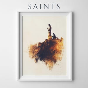 May include: A framed wall art print titled SAINTS featuring a watercolour-style illustration of a figure standing on a rocky cliff with another kneeling figure nearby, rendered in shades of brown, gold, and cream against a light background.
