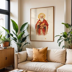 May include: A framed wall art print featuring a watercolor-style illustration of a bearded figure in a red robe with a golden halo, holding two golden spheres. The artwork is displayed on a light-colored wall above a beige sofa with cushions.