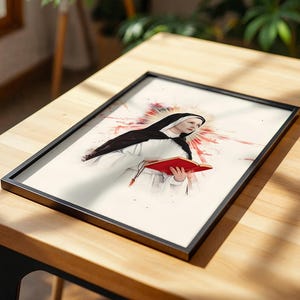 K&ouml;nnte beinhalten: Ein gerahmter Druck mit einer Illustration im Aquarellstil einer Nonne in schwarz-wei&szlig;em Habit, die ein offenes rotes Buch h&auml;lt. Hinter der Figur strahlt ein leuchtend rotes und orangefarbenes Strahlenmuster auf einem cremefarbenen Hintergrund.