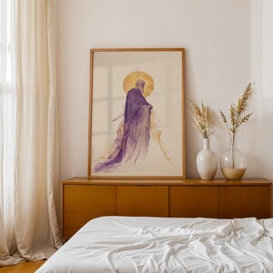 May include: A framed vertical wall art print featuring a watercolour-style illustration of a figure in a flowing purple robe with a golden circular halo behind the head, set against a light cream background within a simple light wood frame.
