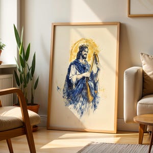 K&ouml;nnte beinhalten: Ein gerahmter Kunstdruck mit einer Aquarell-Illustration einer b&auml;rtigen Figur, die eine Krone und ein flie&szlig;endes blaues Gewand tr&auml;gt und eine goldene Harfe spielt. Das Kunstwerk ist vor einem cremefarbenen Hintergrund mit gelbem Heiligenschein.