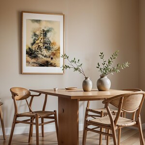 Op de afbeelding: Een ingelijste aquarelprint met een afbeelding van een antieke toren met meerdere verdiepingen, boven een eettafel van licht hout met twee keramische vazen met groene takken, omringd door vier houten stoelen met gevlochten zittingen.
