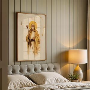 Puede incluir: Una impresi&oacute;n de arte mural enmarcada que presenta una ilustraci&oacute;n estilo acuarela de una figura barbuda con una t&uacute;nica color canela y un halo dorado, sosteniendo un bast&oacute;n de madera. La obra est&aacute; en un marco de madera sobre una pared panelada.