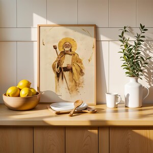 Puede incluir: Una l&aacute;mina enmarcada con una figura barbuda con halo que sostiene un bast&oacute;n, junto a un cuenco de madera con limones amarillos, platos blancos con una cuchara de madera, una taza de cer&aacute;mica blanca y una jarra blanca con hojas verdes.