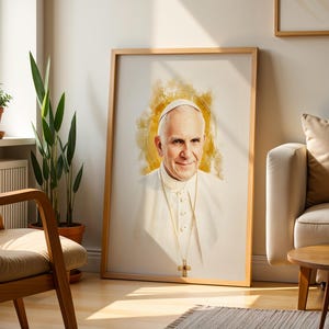 May include: A framed portrait print featuring a watercolour-style illustration of Pope Francis wearing a white cassock and a gold cross necklace, set against a soft, glowing yellow circular background within a light-coloured wooden frame.