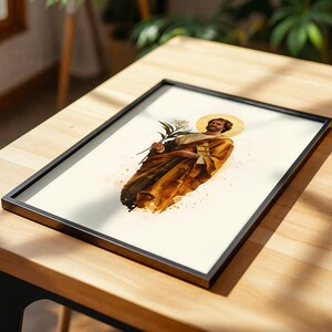 K&ouml;nnte beinhalten: Ein gerahmter Druck mit einer Aquarell-Illustration einer b&auml;rtigen Figur mit goldenem Heiligenschein, die ockerfarbene Gew&auml;nder tr&auml;gt und eine wei&szlig;e Lilie h&auml;lt. Das Kunstwerk ist auf cremefarbenem Grund mit Farbspritzern und dunklen R&auml;ndern.