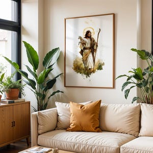 May include: A framed wall art print featuring a watercolour-style illustration of a figure with long brown hair and a beard, wearing robes, holding a small white lamb in one arm and a wooden staff in the other, set against a white background.