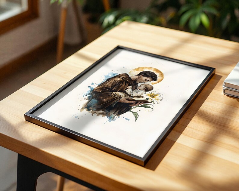 Puede incluir: Una l&aacute;mina art&iacute;stica enmarcada con una ilustraci&oacute;n en acuarela de una persona con t&uacute;nica marr&oacute;n que sostiene a un ni&ntilde;o peque&ntilde;o. Un halo dorado brilla detr&aacute;s de la cabeza de la persona y una flor de lirio blanco se sit&uacute;a en primer plano con salpicaduras.