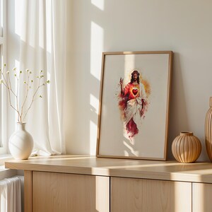 Puede incluir: Una l&aacute;mina de arte mural enmarcada con una ilustraci&oacute;n estilo acuarela de Jesucristo con un Sagrado Coraz&oacute;n rojo brillante. La figura viste t&uacute;nicas blancas y rojas con un halo dorado sobre un fondo beige claro en un marco de madera.