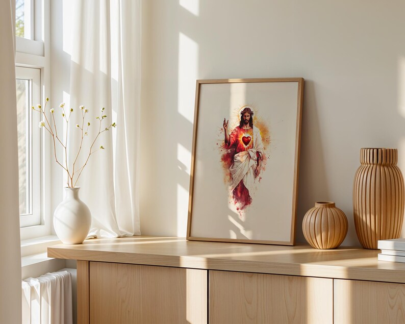 Puede incluir: Una l&aacute;mina de arte mural enmarcada con una ilustraci&oacute;n estilo acuarela de Jesucristo con un Sagrado Coraz&oacute;n rojo brillante. La figura viste t&uacute;nicas blancas y rojas con un halo dorado sobre un fondo beige claro en un marco de madera.