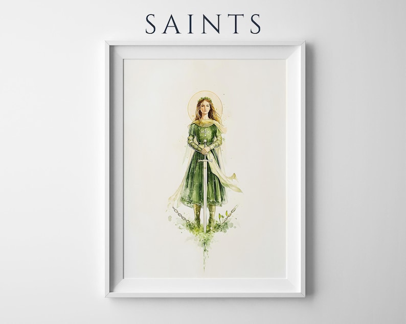 Op de afbeelding: Een ingelijste kunstdruk getiteld SAINTS met een aquarelillustratie van een figuur in een groene jurk die een zwaard vasthoudt. De figuur heeft een gouden halo, vloeiende lichte stof en staat boven gebroken kettingen met groene bladeren.