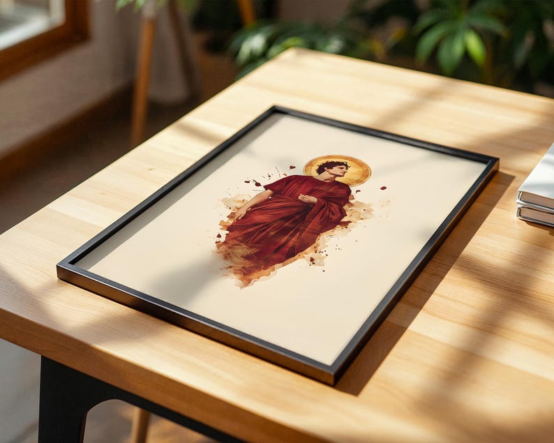 May include: A framed rectangular print featuring a watercolor-style illustration of a figure in a deep red robe with a golden halo behind their head. The artwork is set against a cream-colored background with scattered brown and red paint splatters.