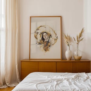 K&ouml;nnte beinhalten: Ein gerahmter Kunstdruck mit einer Aquarellillustration einer Person mit geschlossenen Augen, die eine Geige h&auml;lt, umgeben von goldenen Blumenakzenten und abstrakten kreisf&ouml;rmigen Pinselstrichen in Braun-, Gold- und Blaut&ouml;nen.