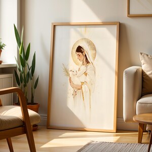 Pode incluir: Uma impress&atilde;o de arte de parede vertical emoldurada com uma ilustra&ccedil;&atilde;o de linhas de uma figura com t&uacute;nica e v&eacute;u brancos, segurando um pequeno cordeiro e uma folha de palmeira. A figura tem uma aur&eacute;ola dourada com detalhes em ouro no design.